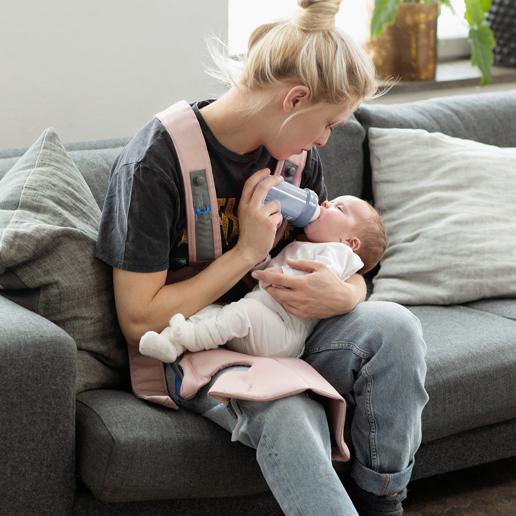 Mom feeding baby with BABYBJÖRN Baby Carrier Mini on mom in -- Color_Dusty Pink Woven