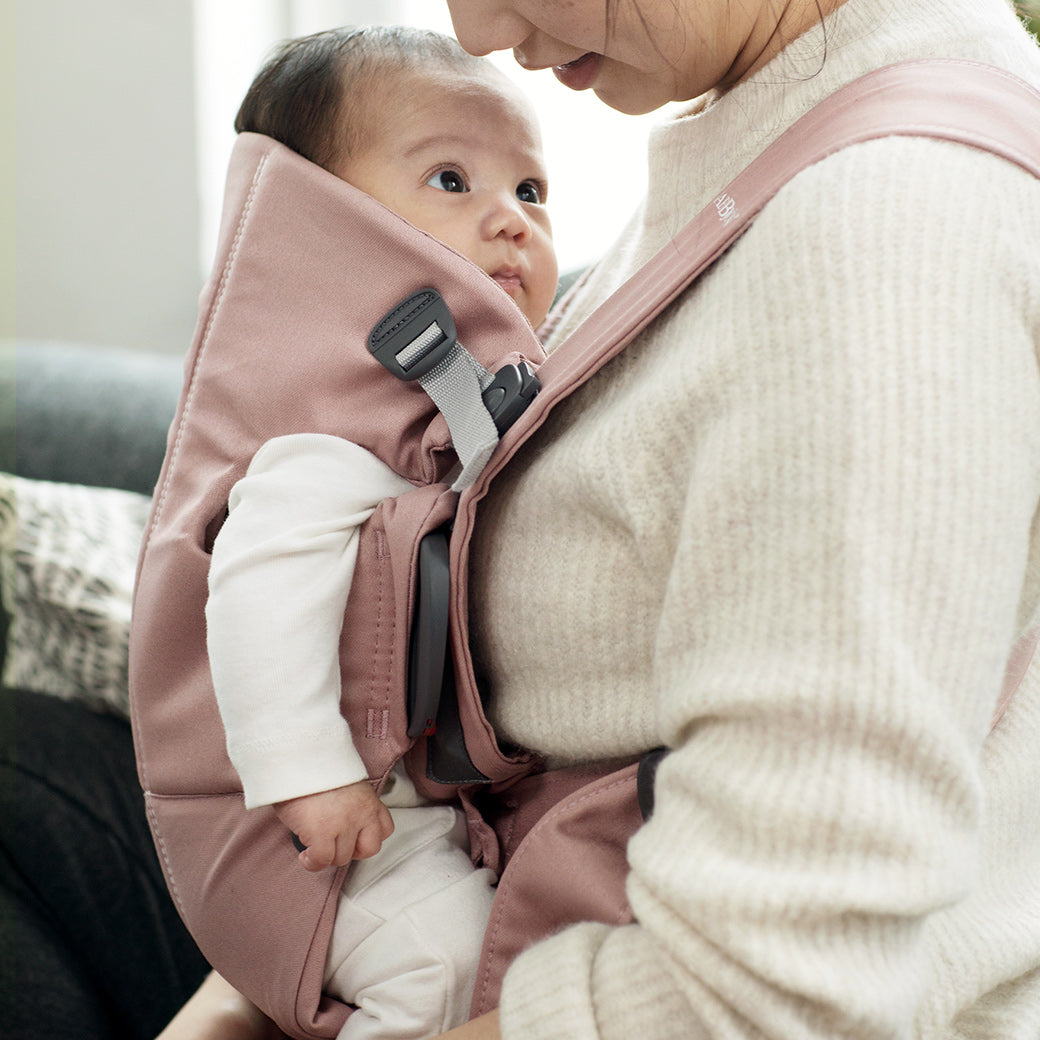 Closeup of mom carrying baby in BABYBJÖRN Baby Carrier Mini in -- Color_Dusty Pink Woven