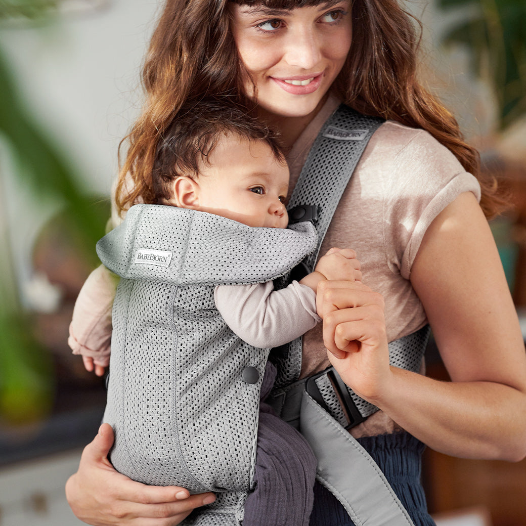 Mom smiling and holding baby in BABYBJÖRN Baby Carrier Mini in -- Color_Grey 3D Mesh