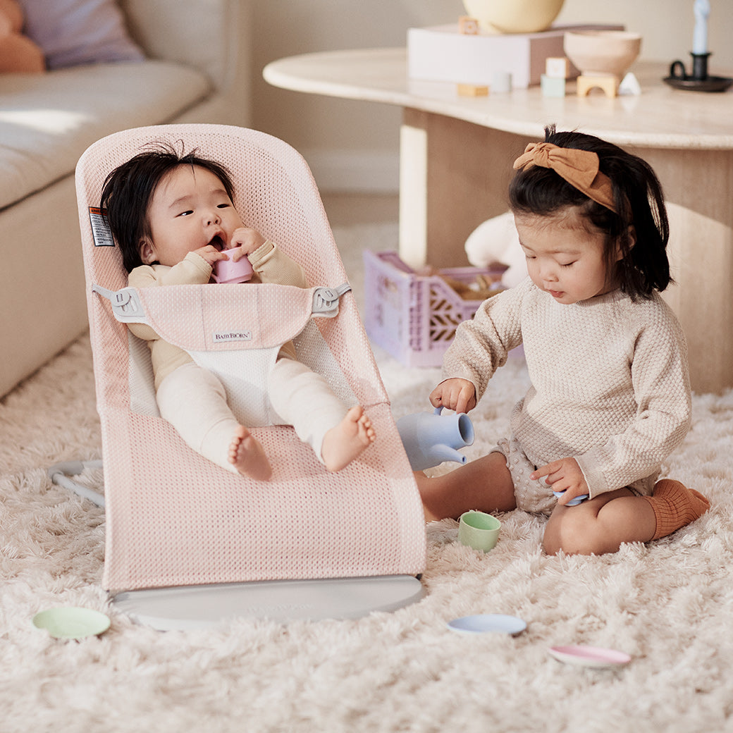 Toddler playing next to baby in BABYBJÖRN Bouncer Balance Soft in -- Color_Pearly Pink/White Mesh
