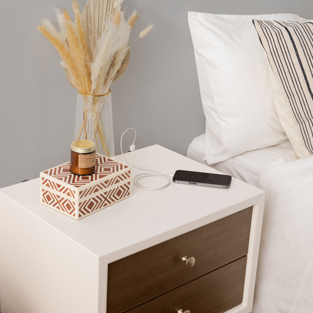 Babyletto's Palma Nightstand With USB Port with a phone charging on it  in -- Color_Warm White with Natural Walnut