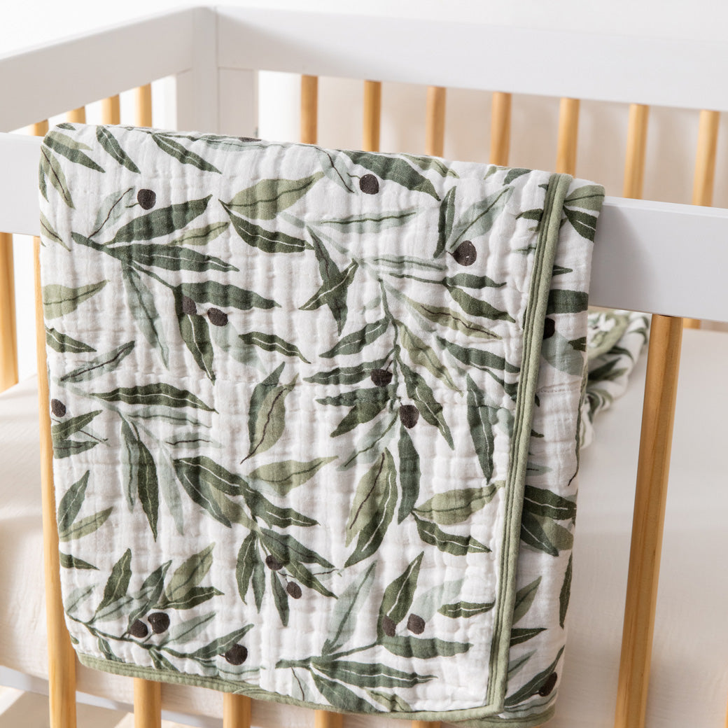 Babyletto's Quilt In 3-Layer GOTS Certified Organic Muslin Cotton over a crib rail in -- Color_Olive Branches
