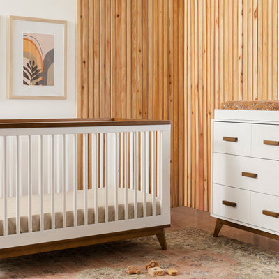 Babyletto's Scoot 3-in-1 Convertible Crib next to dresser  in -- Color_White/Natural Walnut