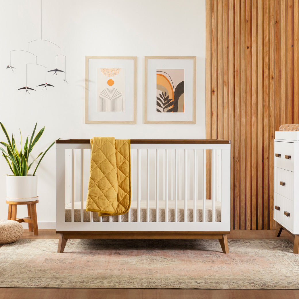Babyletto's Scoot 3-in-1 Convertible Crib with blanket over the rail in -- Color_White/Natural Walnut
