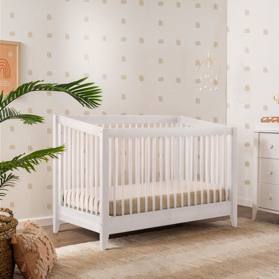 Babyletto's Sprout 4-in-1 Convertible Crib in a nursery next to a dresser in -- Color_White