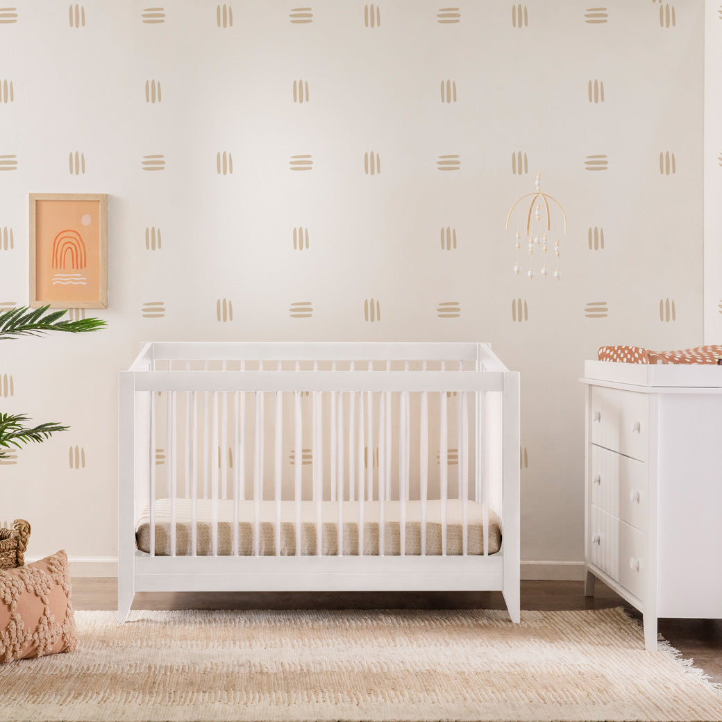 Front view of Babyletto's Sprout 4-in-1 Convertible Crib next to a dresser  in -- Color_White