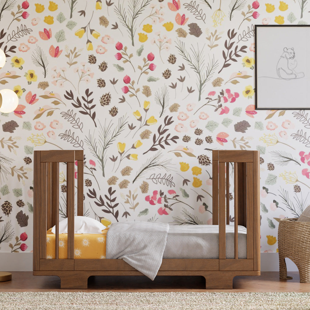 Babyletto's Yuzu 8-In-1 Convertible Crib as a bed in a floral room in -- Color_Natural Walnut