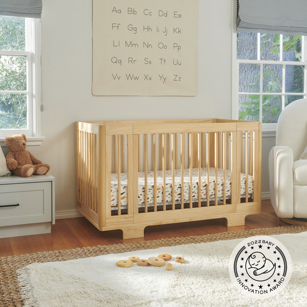 Babyletto's Yuzu 8-In-1 Convertible Crib next to a recliner in -- Color_Natural 