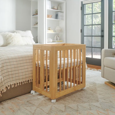 Babyletto's Yuzu 8-In-1 Convertible Crib next to a bed in -- Color_Natural