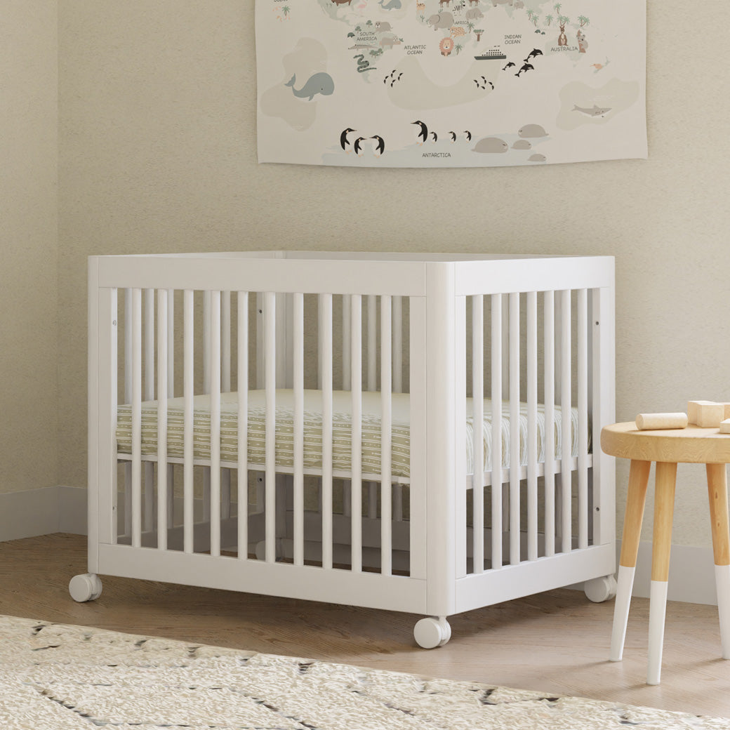Babyletto's Yuzu 8-In-1 Convertible Crib With All Stages Conversion Kits next to a table in -- Color_White