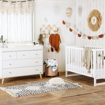 Dadada Austin 5-Drawer Dresser  in a baby room next to a crib in -- Color_White/Natural