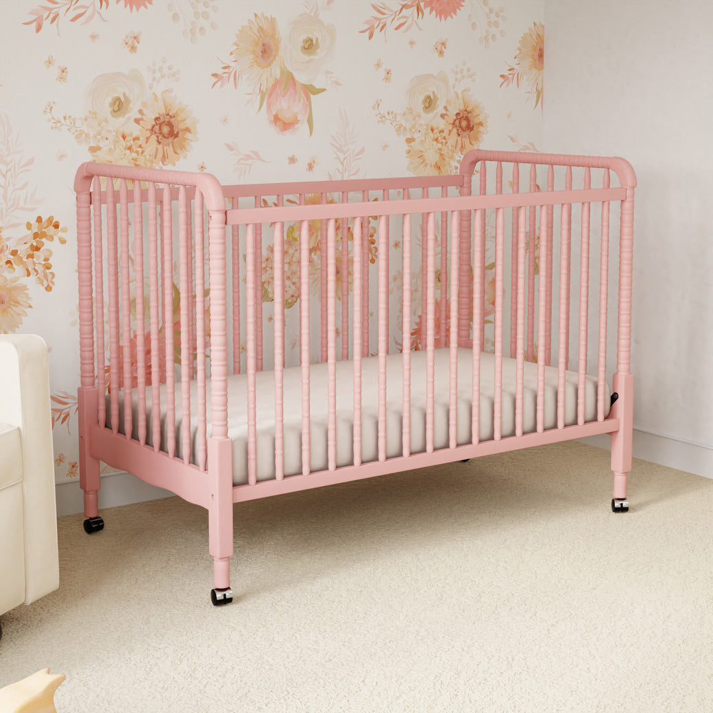 Lifestyle side view of the DaVinci’s Jenny Lind Crib in a floral room in -- Color_Blush Pink