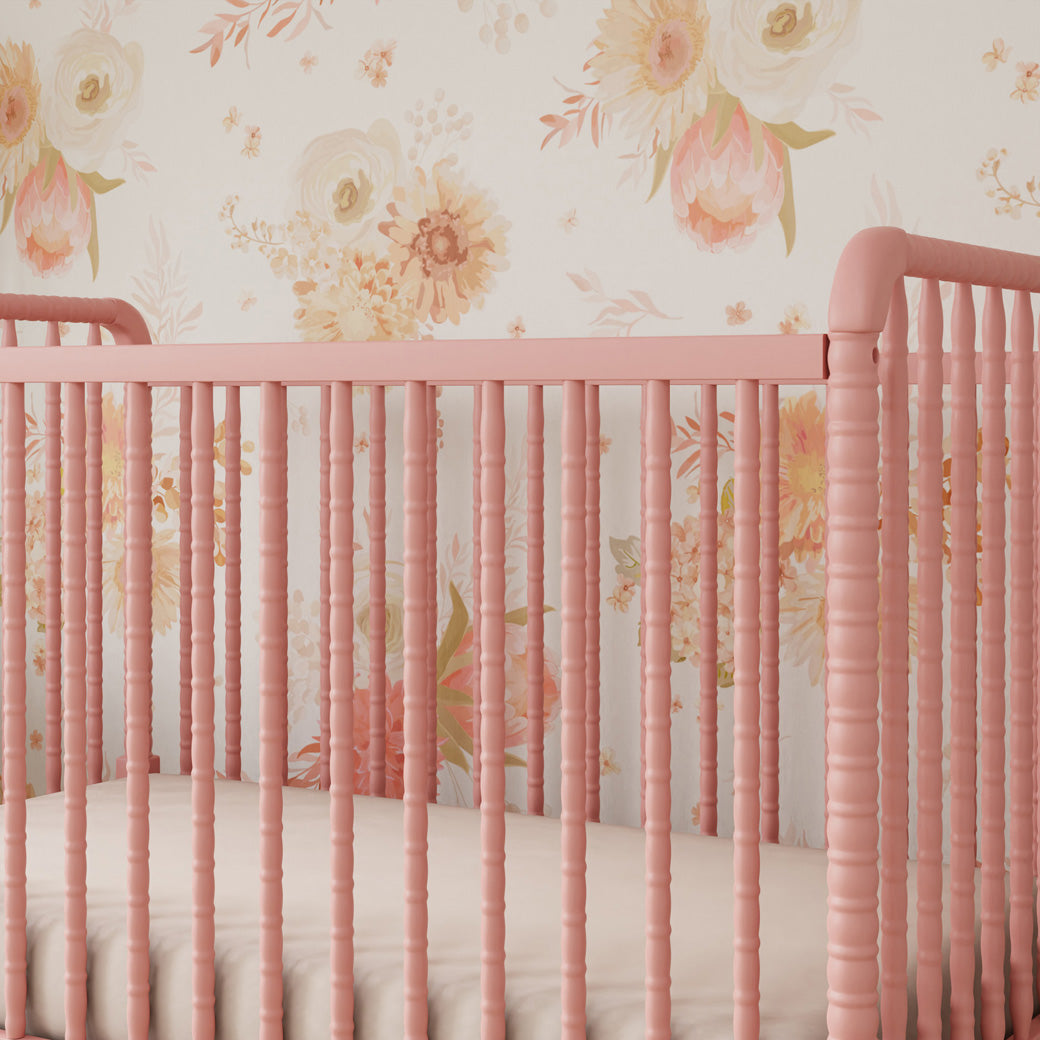Lifestyle closeup view of the rails of the DaVinci’s Jenny Lind Crib in a floral room in -- Color_Blush Pink