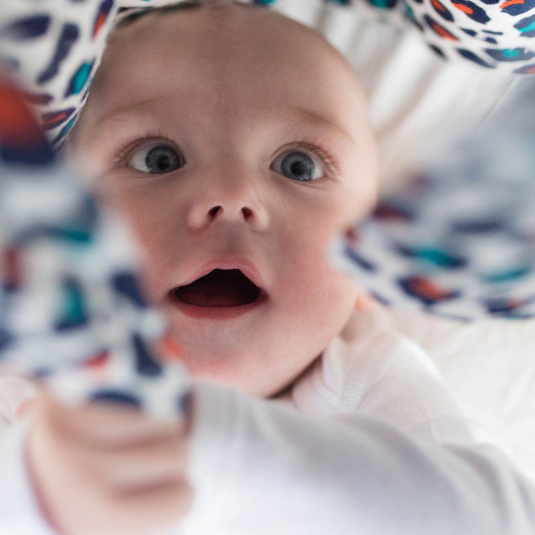 Baby looking at and playing with The Etta Loves Sensory Muslin in -- Color_Leopard