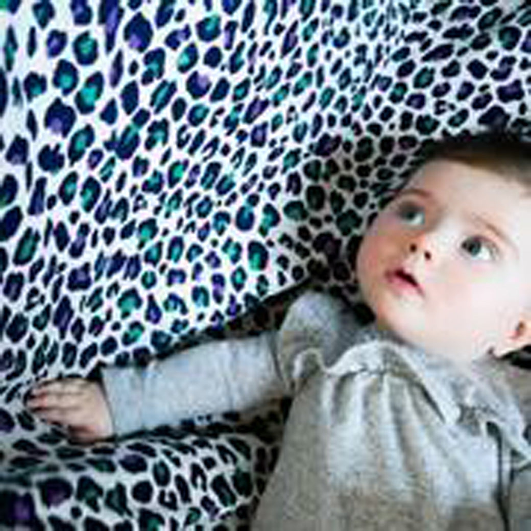 Baby looking at the The Etta Loves Sensory Muslin in -- Color_Leopard