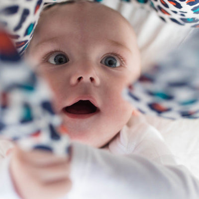 Baby looking at and playing with The Etta Loves Sensory Muslin in -- Color_Leopard