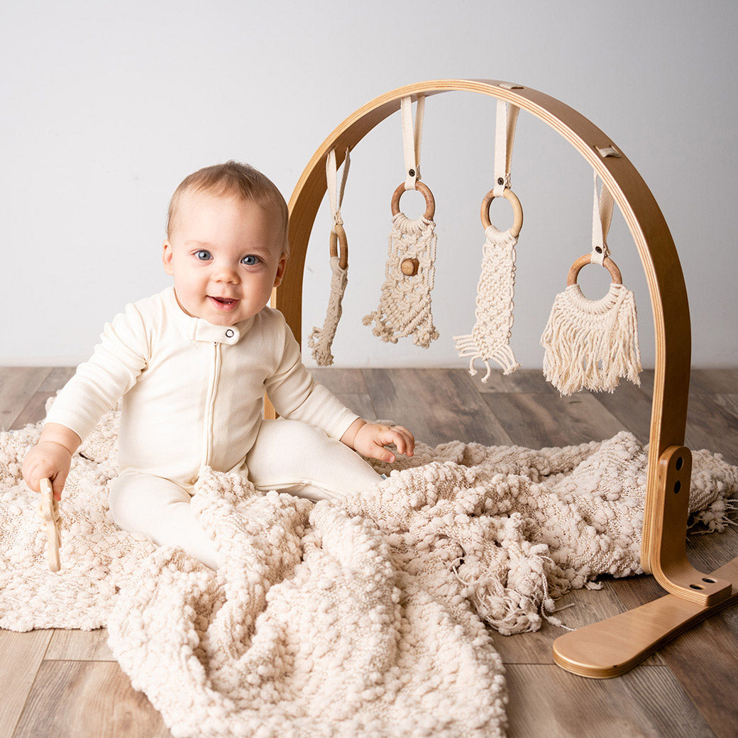 A baby sitting next to the Finn and Emma Play Gym in -- Color_Natural _ Macrame