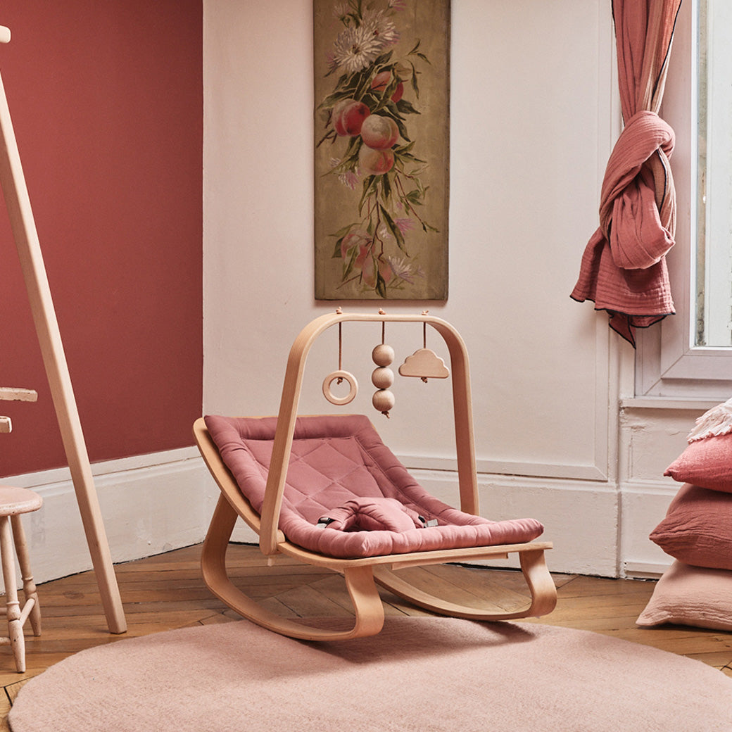 Charlie Crane LEVO Baby Rocker in a rose colored room with an Activity Arch attached to it  -- Color_Bois de Rose _ Beech