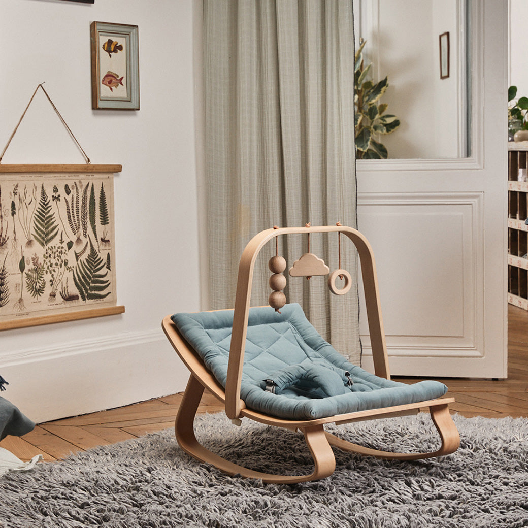 Charlie Crane LEVO Baby Rocker in a cozy room with an Activity Arch attached to it   -- Color_Orage _ Walnut