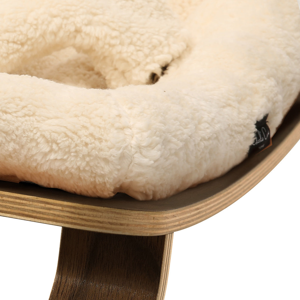 Up close of the front edge on the Charlie Crane LEVO Baby Rocker in -- Color_Fur Milk _ Walnut
