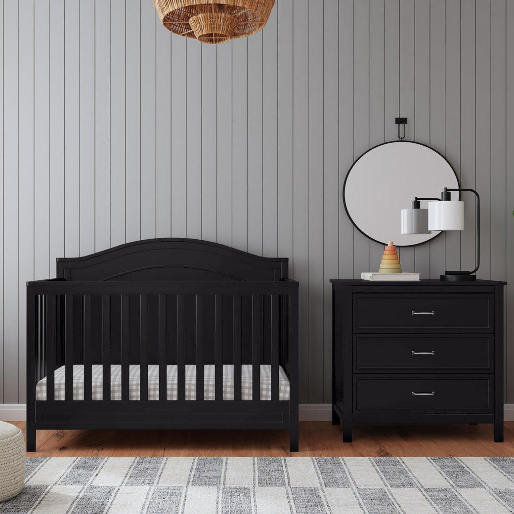 The DaVinci Charlie 4-in-1 Convertible Crib next to a dresser in -- Color_Ebony