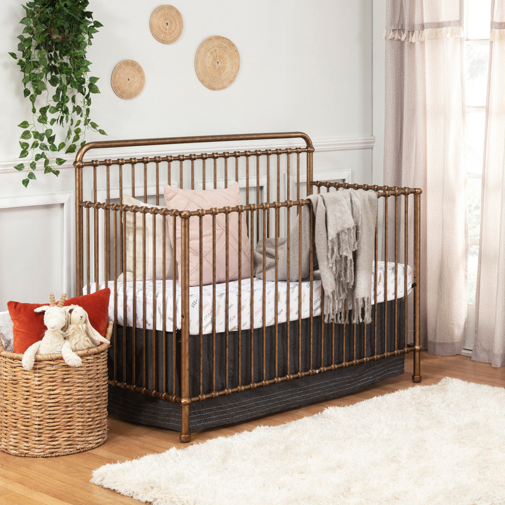Namesake's Winston 4 in 1 Convertible Crib in a room with a blanket over the rail  in -- Color_Vintage Gold