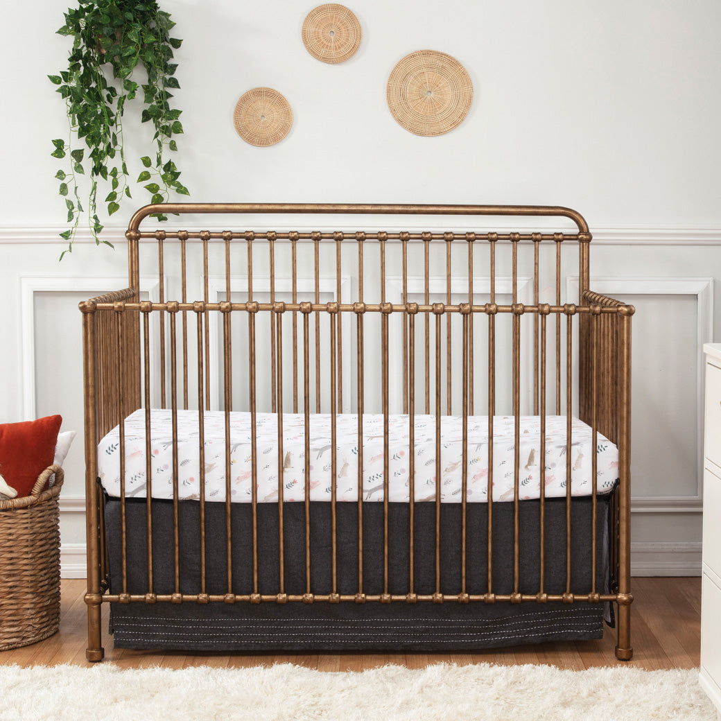 Namesake's Winston 4 in 1 Convertible Crib next to a basket  in -- Color_Vintage Gold