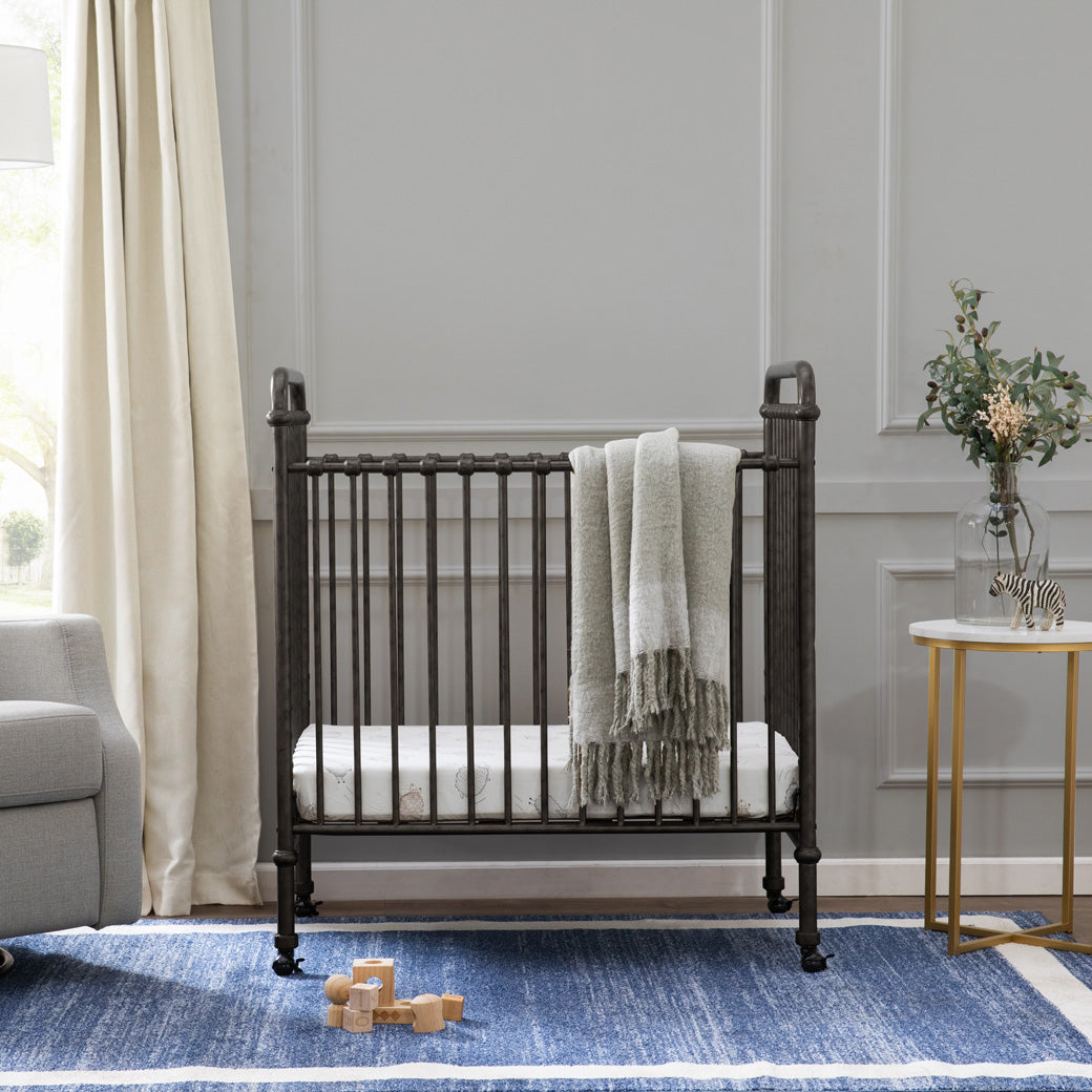 Namesake`s Abigail 3-in-1 Convertible Mini Crib with a blanket on the rail  in -- Color_Vintage Iron