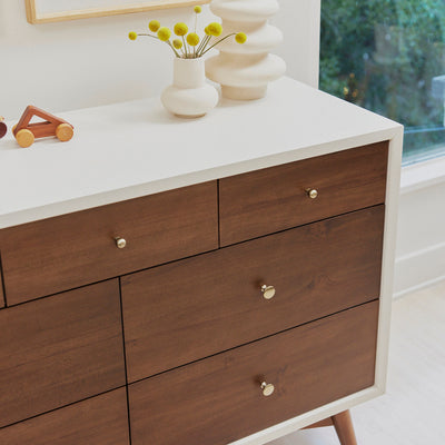 Babyletto's Palma 7-Drawer Assembled Double Dresser closeup next to a window in -- Color_Warm White with Natural Walnut