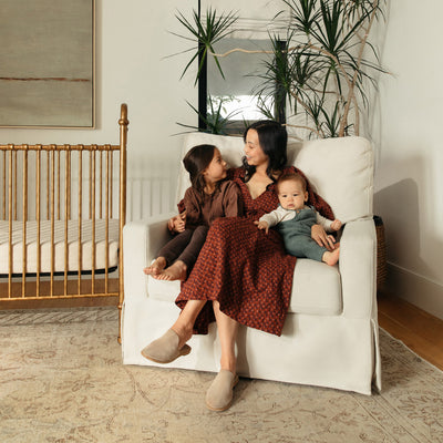 Mother with two kids sitting in The Namesake's Crawford Pillowback Chair-And-A-Half Comfort Swivel Glider in -- Color_Performance Cream Eco-Weave