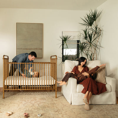 Mother sitting with a child in The Namesake's Crawford Pillowback Chair-And-A-Half Comfort Swivel Glider in -- Color_Performance Cream Eco-Weave