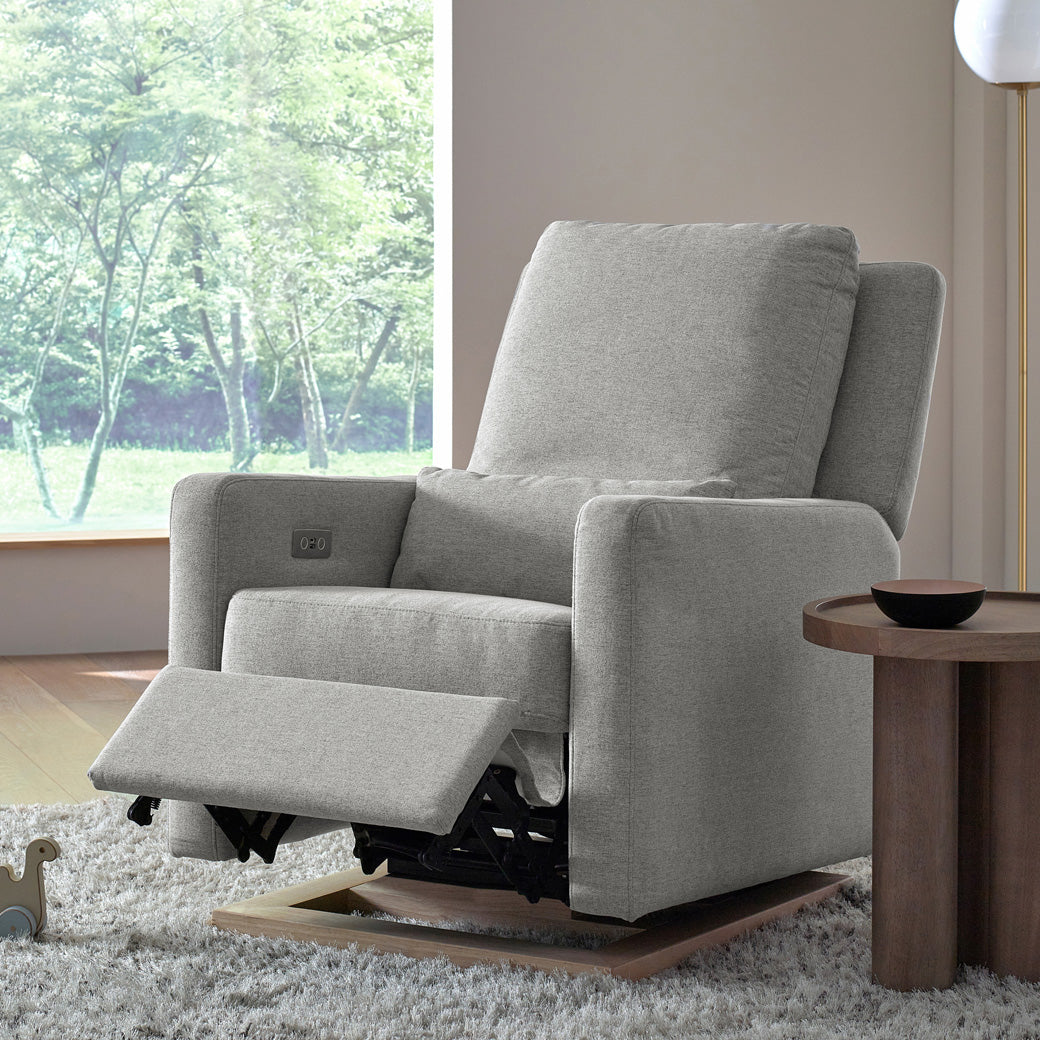 Babyletto Sigi Electronic Glider Recliner with footrest up next to a coffee table in -- Color_Performance Grey Eco-Weave