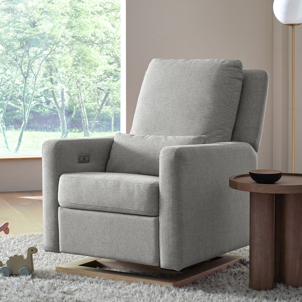 Babyletto Sigi Electronic Glider Recliner next to a coffee table and window in -- Color_Performance Grey Eco-Weave
