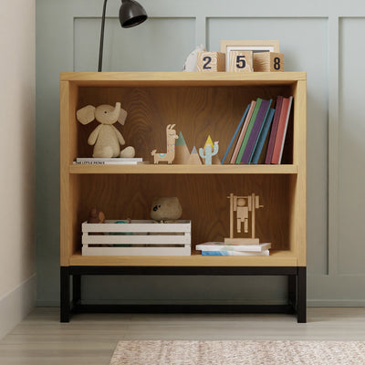 Front view of DaVinci's Ryder Convertible Cubby Changer & Bookcase with items on it in -- Color_Honey