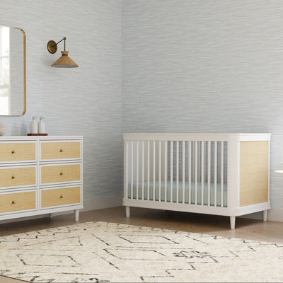 The Namesake Marin 3-in-1 Convertible Crib next to dresser  in -- Color_Warm White/Honey Cane