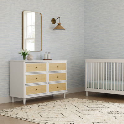 Namesake's Marin 6 Drawer Dresser under a mirror next to a crib in -- Color_Warm White/Honey Cane