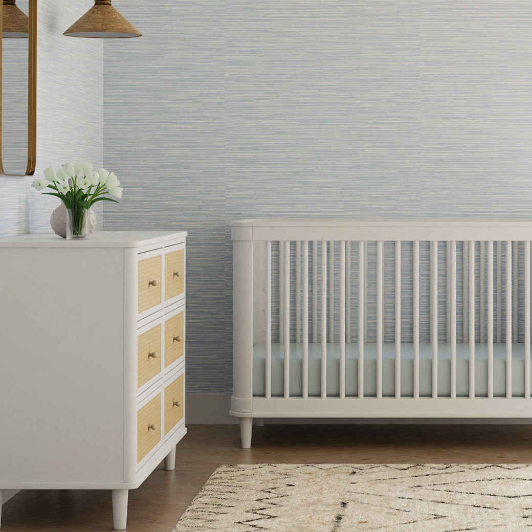 Namesake's Marin 6 Drawer Dresser next to a crib with flowers on it  in -- Color_Warm White/Honey Cane