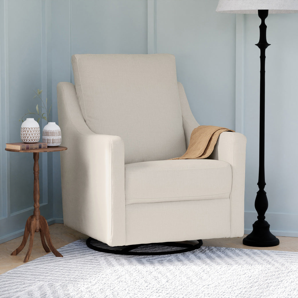 Lifestyle side view of The DaVinci Field Swivel Glider next to a table and lamp in --Color_Cotton Weave