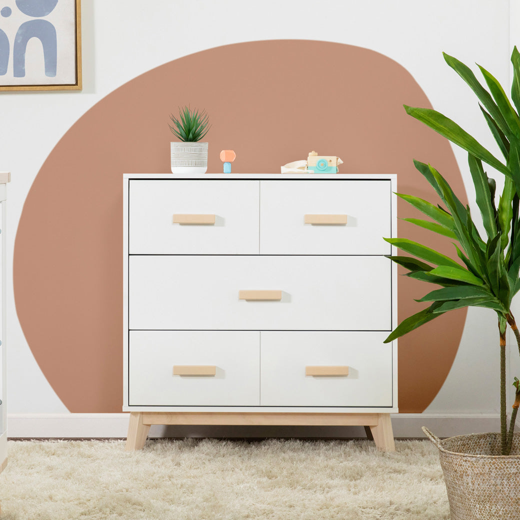 Babyletto's Scoot 3-Drawer Changer Dresser in a room with items on it in  -- Color_Washed Natural/White