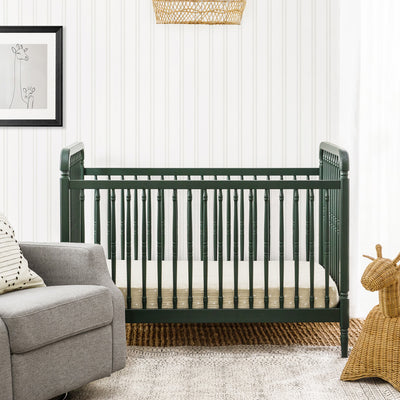 Lifestyle front view of The Namesake Liberty 3-in-1 Convertible Spindle Crib next to chair in -- Color_Forest Green