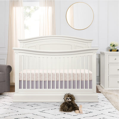 Namesake's Durham 4-in-1 Convertible Crib next to a window and dresser  in -- Color_Warm White