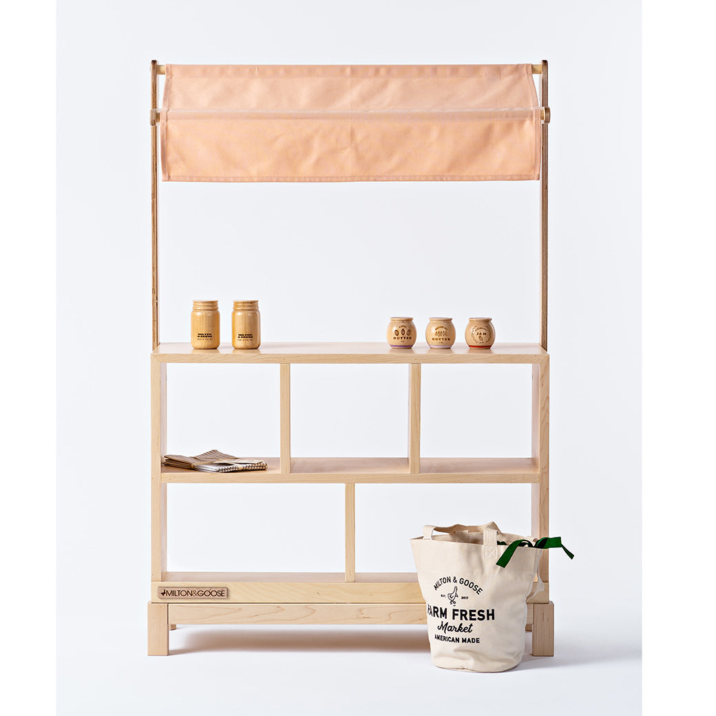 Milton & Goose Market Stand with items on it and tote bag in front  in -- Color_Natural / Pink