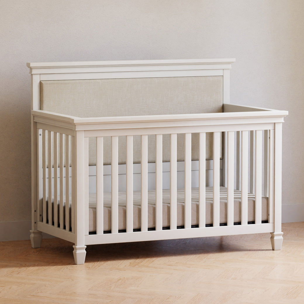 Darlington 4-in-1 Convertible Crib in Warm White next to a wall