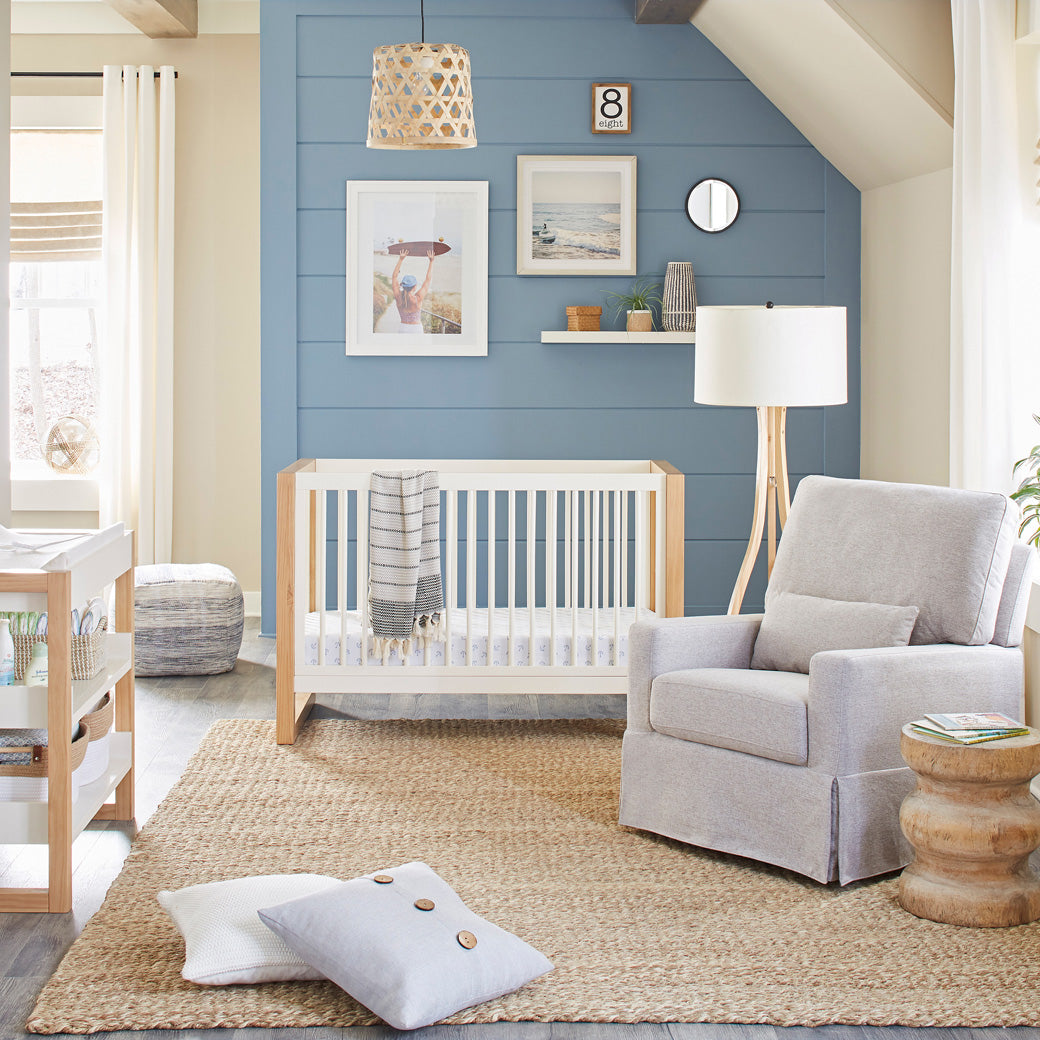 Namesake's Nantucket 3-in-1 Convertible Crib next to a recliner in -- Color_Warm White/Honey