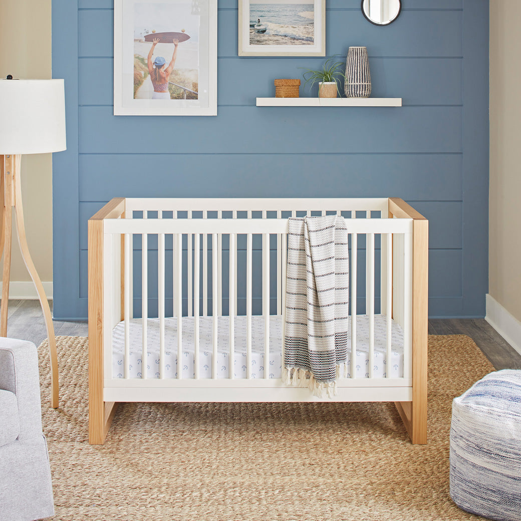 Front view of Namesake's Nantucket 3-in-1 Convertible Crib with a blanket on rail  in -- Color_Warm White/Honey