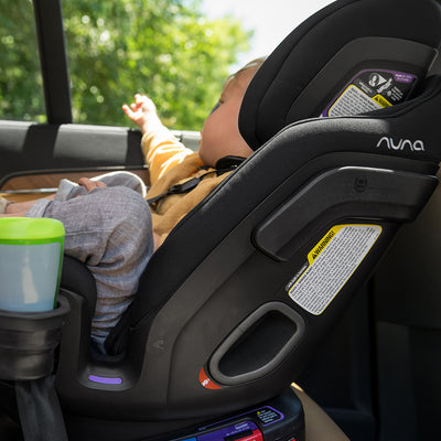 Baby sitting in the Nuna EXEC Car Seat in Color_Ocean in the back of a car — All