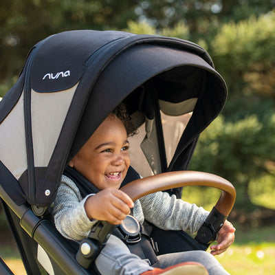 A cute little boy having fun in the Nuna DEMI Grow stroller and PIPA series travel system in -- Color_Caviar / PIPA