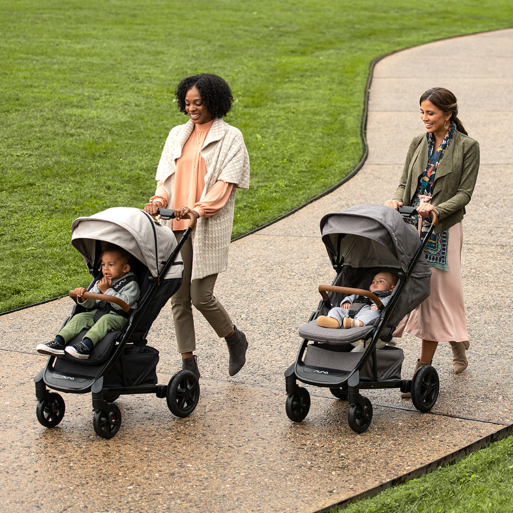 Two young moms walking with their kids in the TAVO Next stroller and PIPA Series travel system in -- All