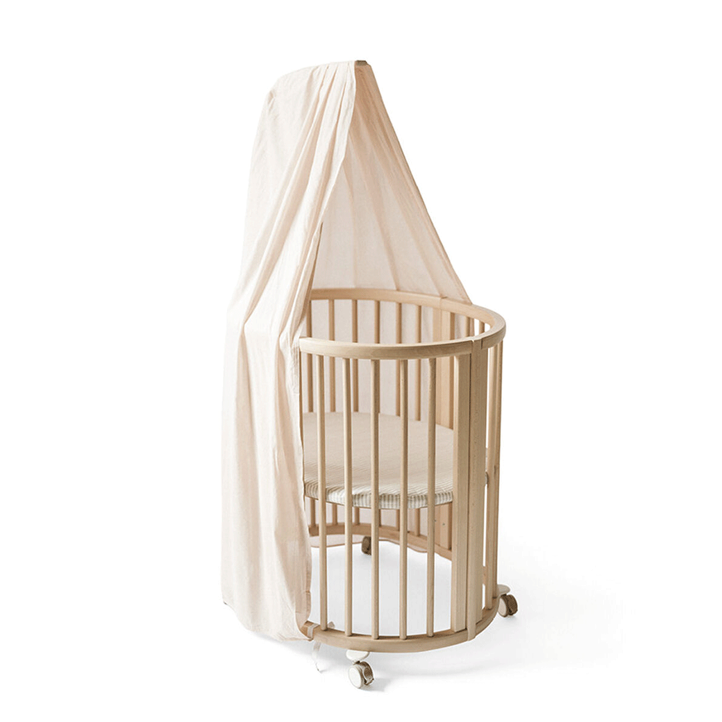 A crib equipped with the Stokke Sleepi V3 Canopy by Pehr in -- Color_Blush