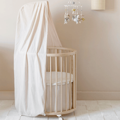 An empty crib equipped with the Stokke Sleepi V3 Canopy by Pehr in -- Color_Blush